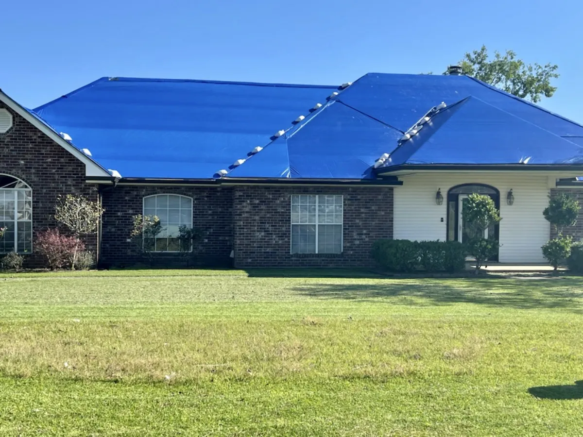 Blue emergency tarp on residential brick home
